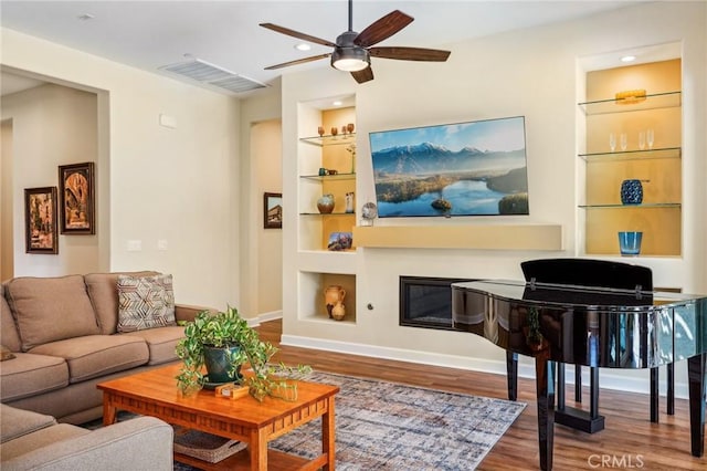 living room featuring ceiling fan, built in features, and hardwood / wood-style floors