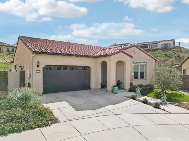 mediterranean / spanish home featuring a garage, a tiled roof, driveway, and stucco siding