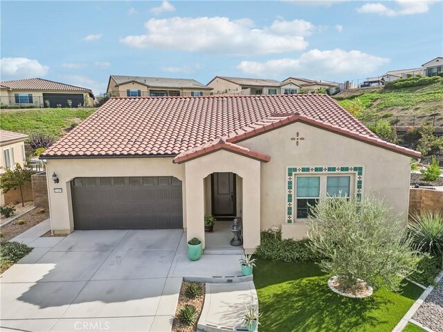 mediterranean / spanish home featuring driveway, a tiled roof, a garage, and stucco siding