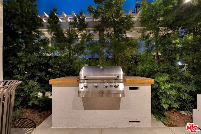 patio at night featuring an outdoor kitchen and area for grilling