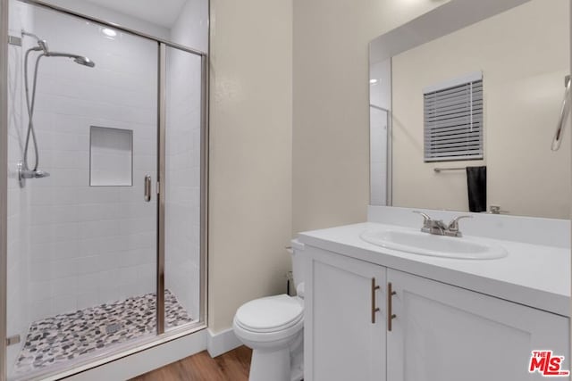 bathroom with hardwood / wood-style flooring, vanity, toilet, and an enclosed shower