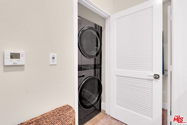 laundry area with light hardwood / wood-style floors and stacked washing maching and dryer