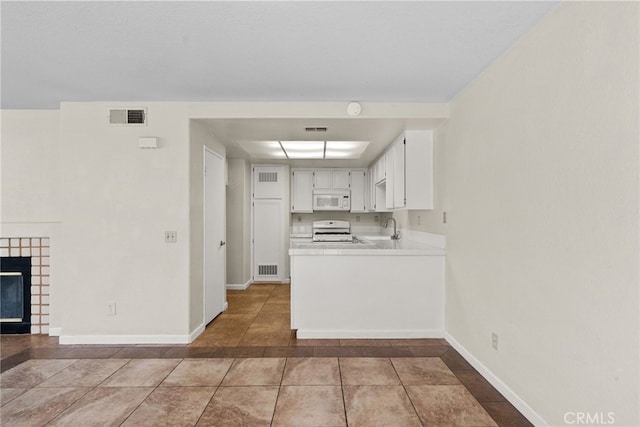 kitchen with a tile fireplace, white cabinetry, sink, kitchen peninsula, and white appliances