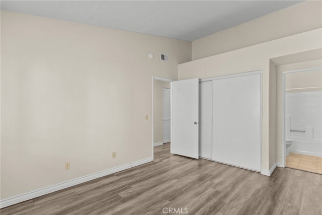 unfurnished bedroom with light hardwood / wood-style floors, connected bathroom, and a closet