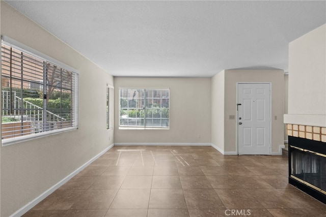 unfurnished living room featuring tile patterned flooring, a fireplace, and a textured ceiling