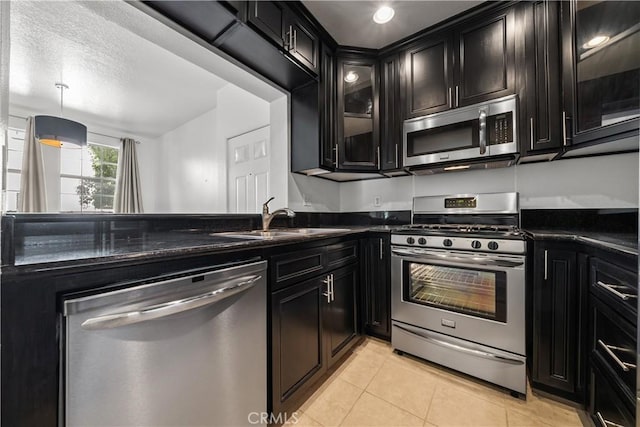 kitchen with a textured ceiling, stainless steel appliances, sink, light tile patterned floors, and hanging light fixtures