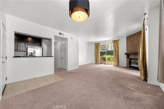 unfurnished living room featuring a large fireplace and light carpet