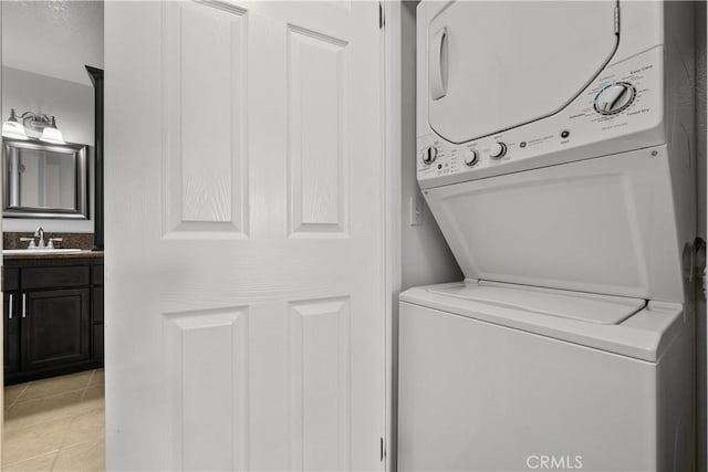 clothes washing area featuring light tile patterned floors, stacked washer and clothes dryer, and sink