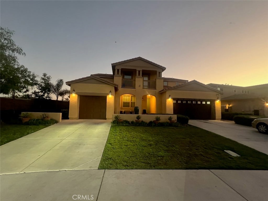 view of front of house with a balcony, a garage, and a lawn