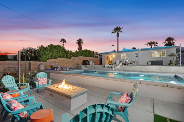 pool at dusk with a patio area, pool water feature, and an outdoor fire pit