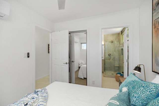 bedroom with ensuite bath, a wall unit AC, and ceiling fan