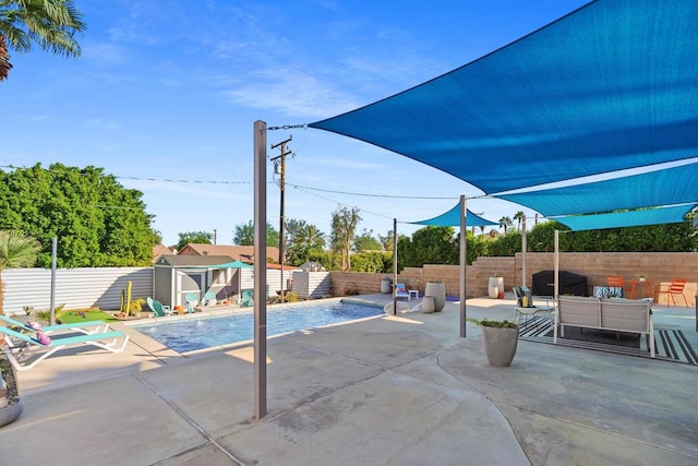 view of pool with outdoor lounge area, a patio area, and a storage shed