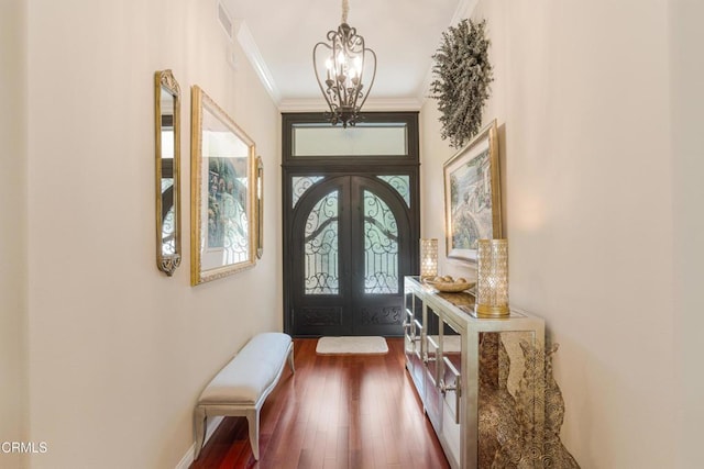 doorway with dark wood-type flooring, a chandelier, crown molding, and french doors