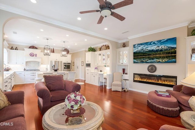 living room featuring ceiling fan, dark wood-type flooring, and crown molding