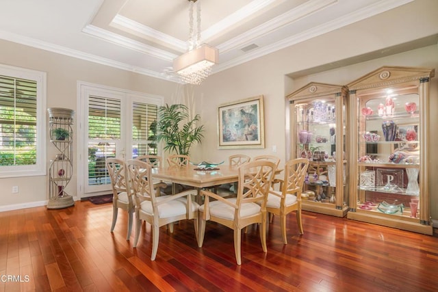 dining room with hardwood / wood-style floors, a tray ceiling, crown molding, and a notable chandelier