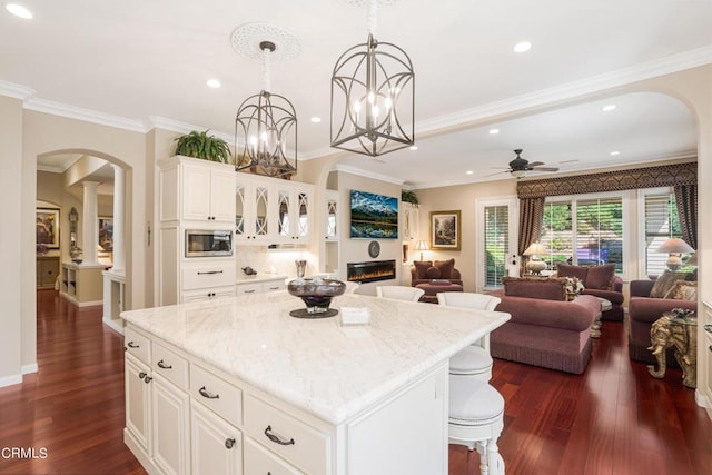 kitchen featuring stainless steel microwave, white cabinets, ceiling fan, and a kitchen island