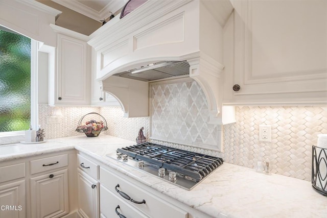 kitchen with stainless steel gas stovetop, backsplash, white cabinets, and light stone countertops