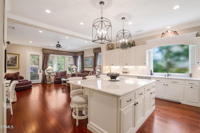 kitchen featuring pendant lighting, a kitchen island, white cabinets, dark hardwood / wood-style flooring, and ceiling fan with notable chandelier