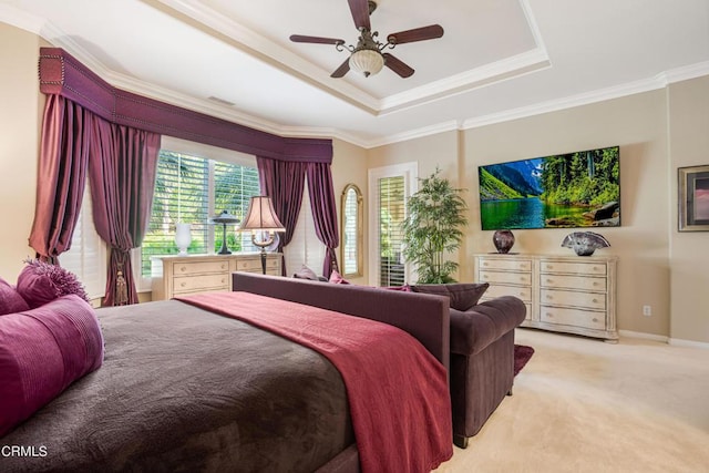 bedroom with ceiling fan, a tray ceiling, ornamental molding, and light carpet