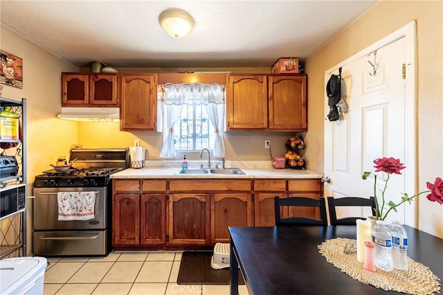 kitchen with gas range, light tile patterned flooring, and sink