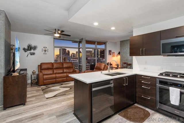 kitchen featuring light hardwood / wood-style floors, kitchen peninsula, appliances with stainless steel finishes, dark brown cabinetry, and sink