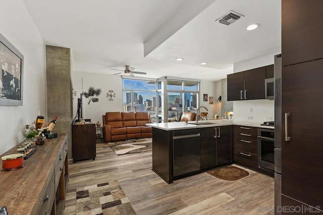 kitchen with stainless steel appliances, light hardwood / wood-style floors, kitchen peninsula, and sink