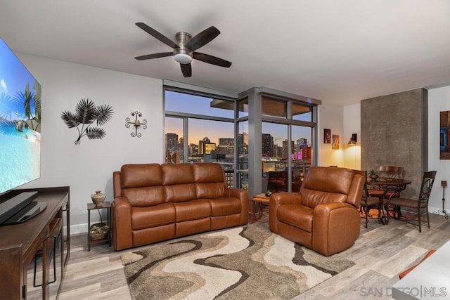 living room with light wood-type flooring, ceiling fan, and a healthy amount of sunlight