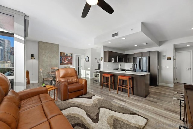 living room with ceiling fan, light hardwood / wood-style floors, and sink