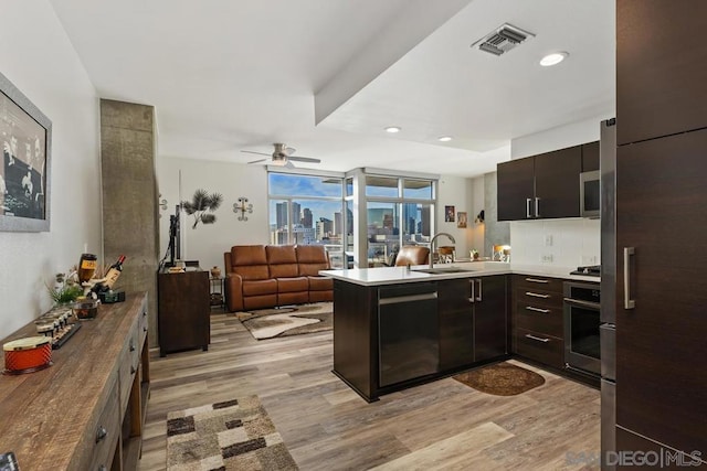 kitchen with sink, light hardwood / wood-style flooring, black appliances, and kitchen peninsula