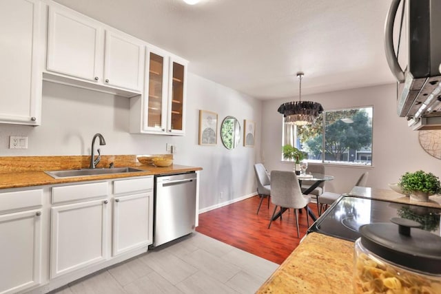 kitchen featuring sink, white cabinetry, stainless steel appliances, decorative light fixtures, and light wood-type flooring