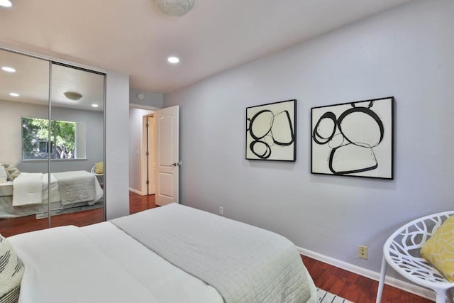 bedroom with dark hardwood / wood-style floors and a closet