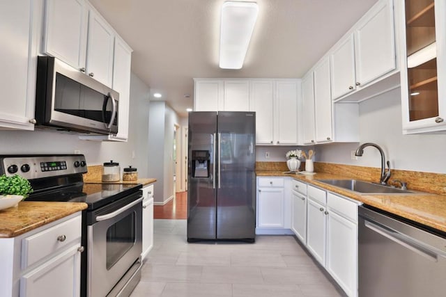 kitchen with light stone countertops, white cabinetry, appliances with stainless steel finishes, and sink