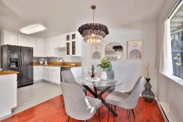 dining room featuring sink, a notable chandelier, a baseboard radiator, and light wood-type flooring