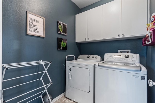 clothes washing area with cabinets and washing machine and dryer