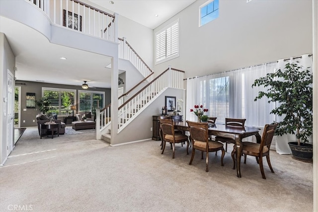 carpeted dining space with a high ceiling, a healthy amount of sunlight, and ceiling fan