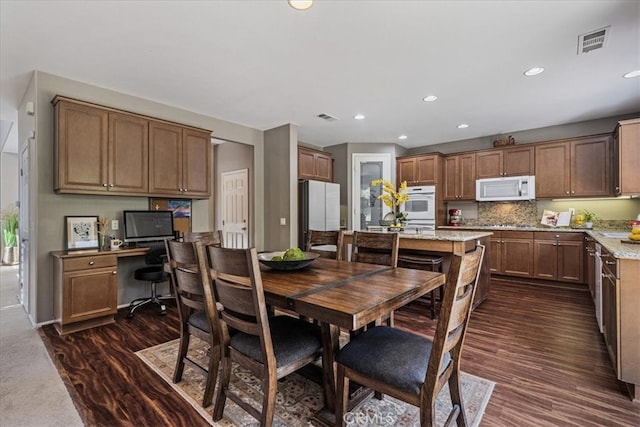 dining space with built in desk and dark wood-type flooring