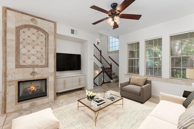 living room with ceiling fan and a tile fireplace