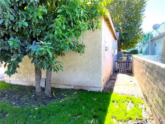 view of side of home with fence and stucco siding