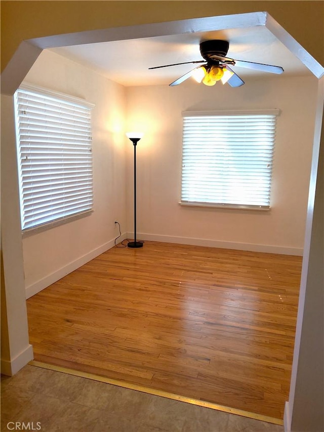 empty room featuring a ceiling fan, baseboards, and wood finished floors