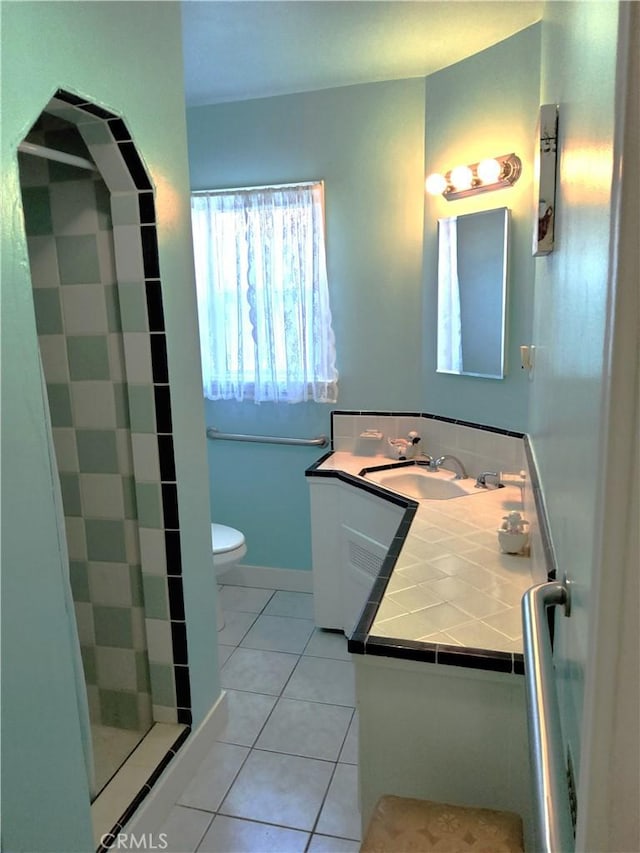 bathroom with tile patterned flooring, baseboards, vanity, and toilet