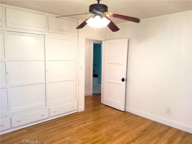 unfurnished bedroom featuring light wood-style floors, a closet, baseboards, and a ceiling fan