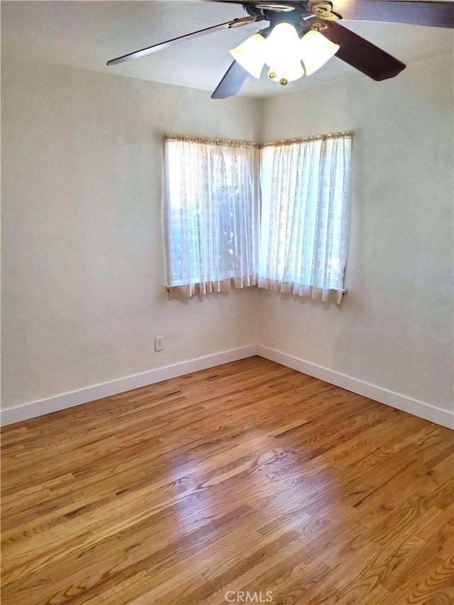 spare room with a ceiling fan, light wood-style flooring, baseboards, and a wealth of natural light