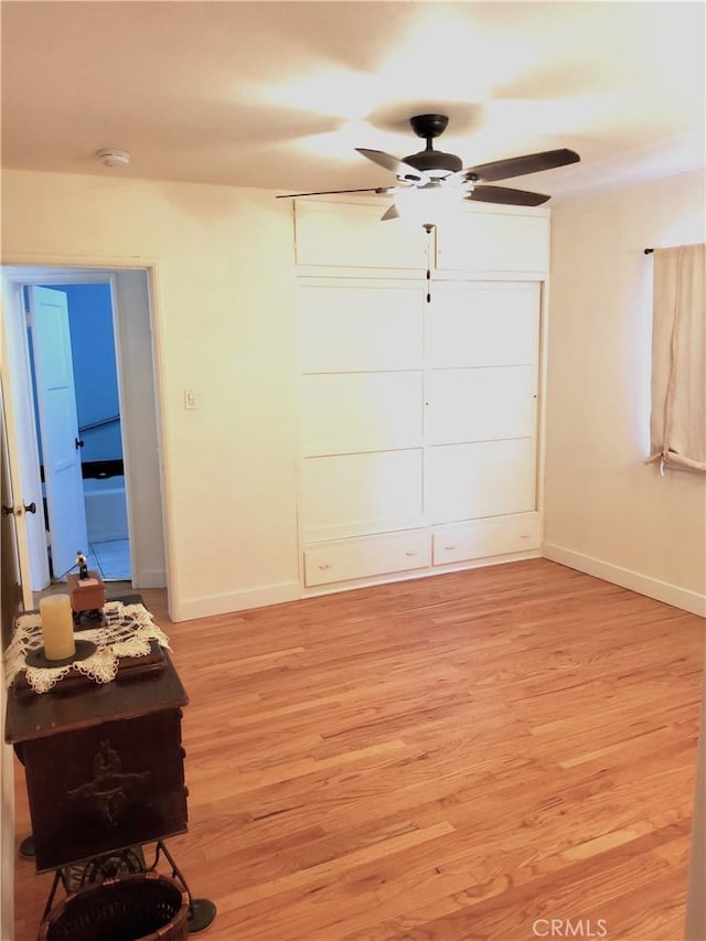 bedroom featuring ceiling fan, light wood-style flooring, and baseboards