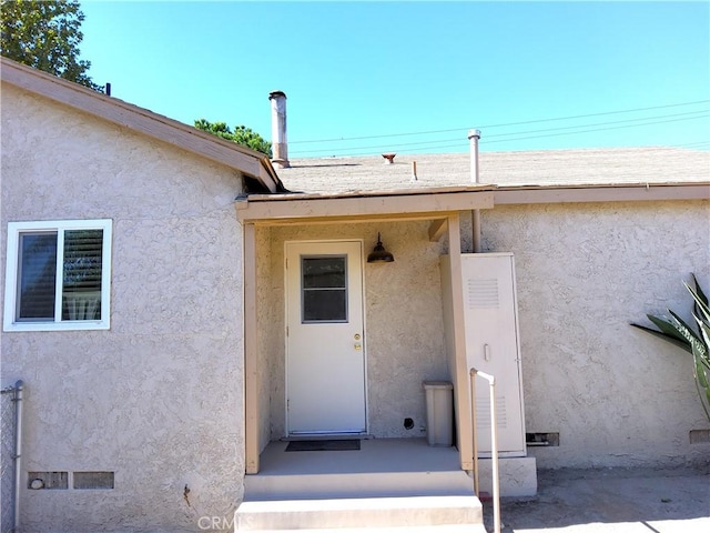 entrance to property featuring crawl space and stucco siding