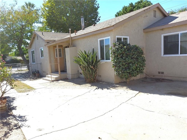 rear view of house with crawl space, a patio, fence, and stucco siding