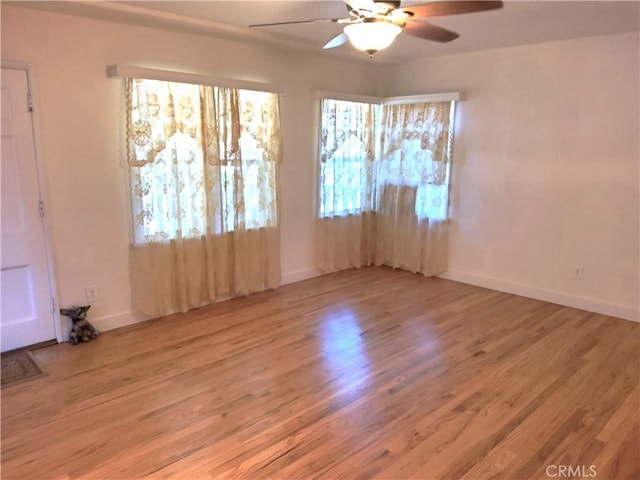 empty room featuring ceiling fan, light wood-style flooring, and baseboards