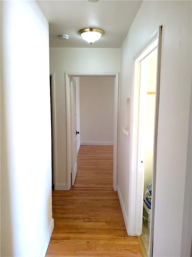 corridor featuring light wood-style flooring and baseboards