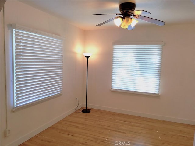 unfurnished room with baseboards, ceiling fan, and light wood-style floors