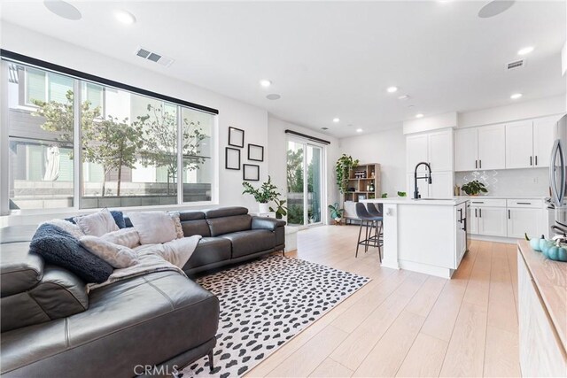 living room featuring sink and light hardwood / wood-style flooring