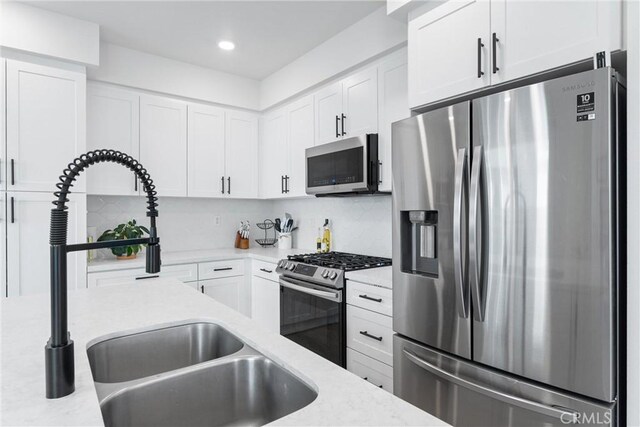 kitchen with decorative backsplash, light stone countertops, stainless steel appliances, sink, and white cabinets